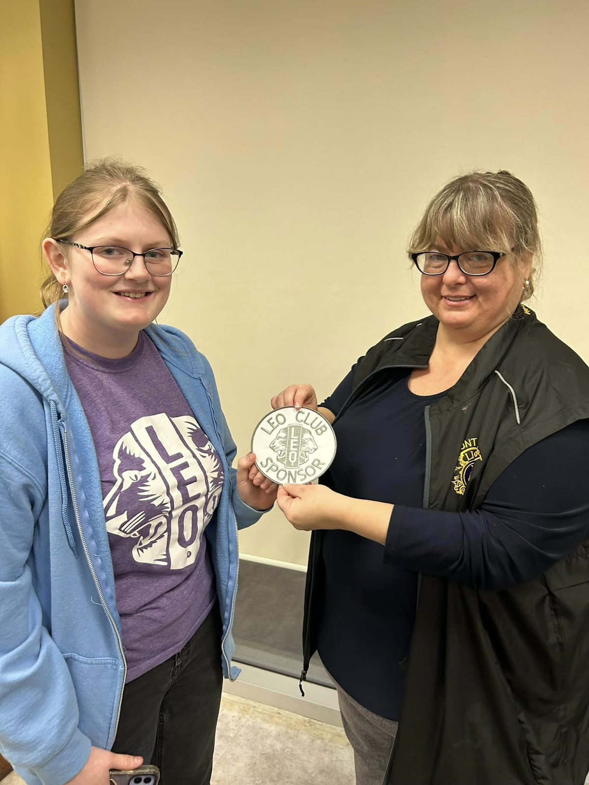 This photo features Abigail G. receiving a Little Lions plaque from another woman. 